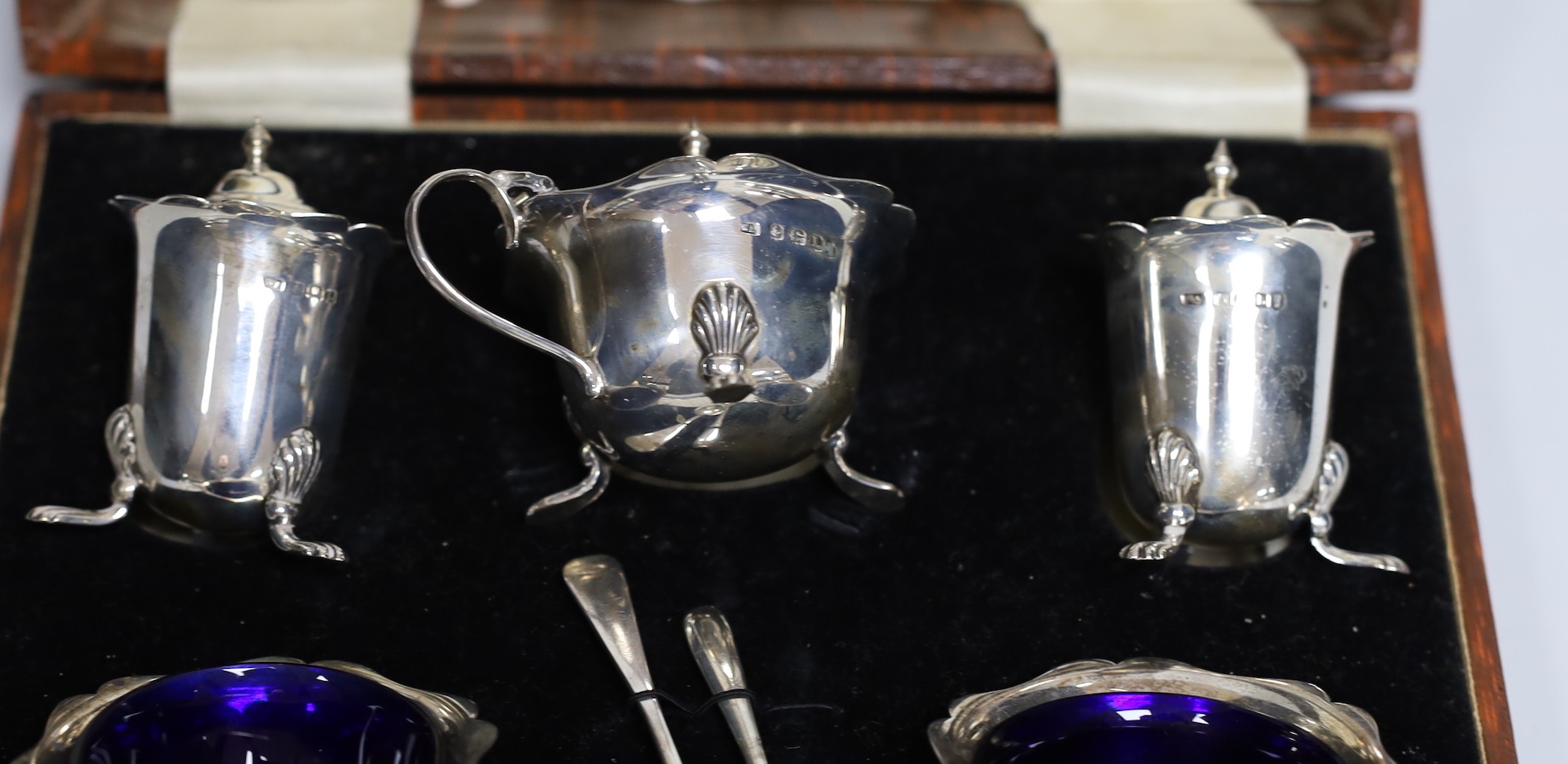 A cased 1930's silver five piece condiment set, with two associated silver spoons.
